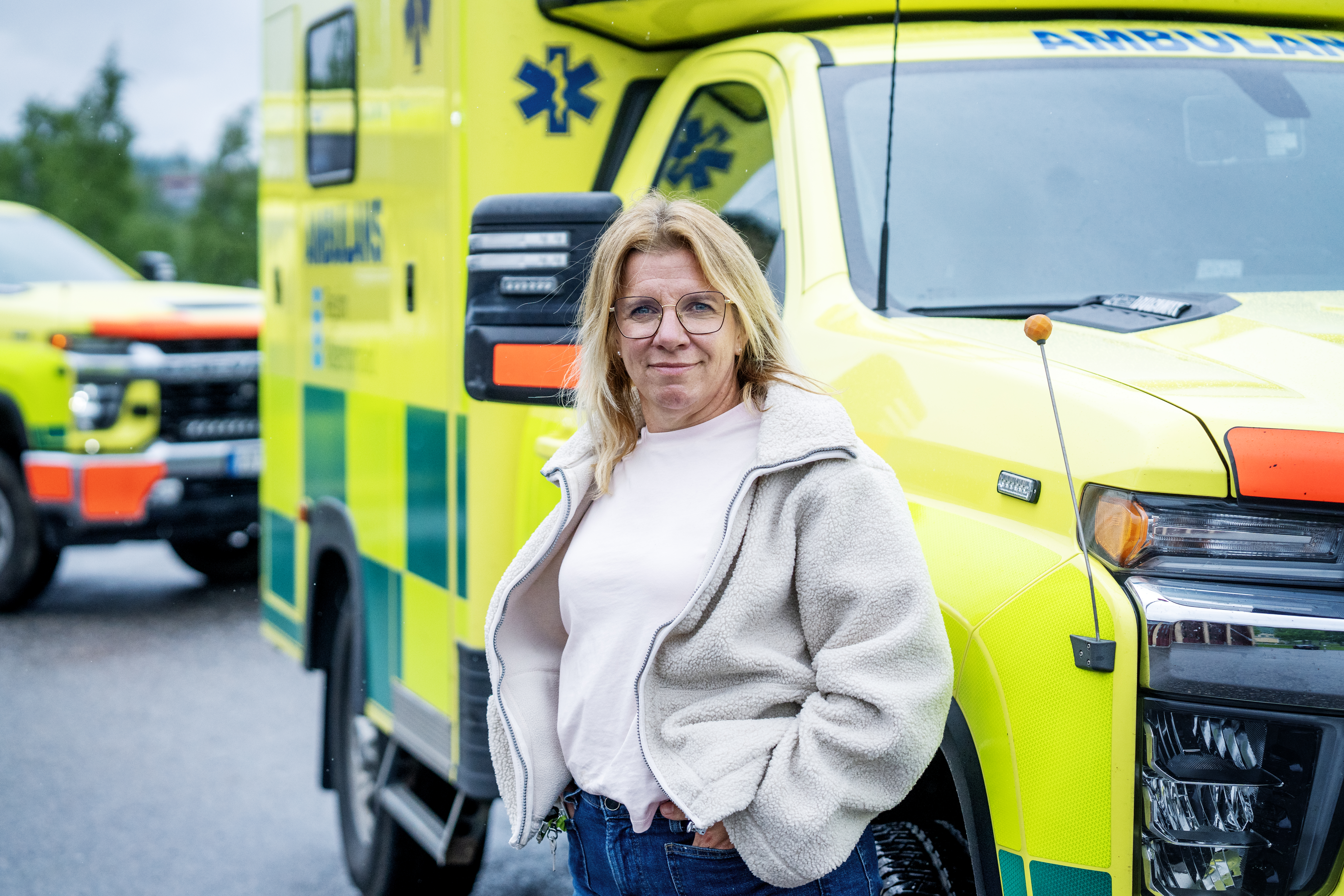 Kvinna står framför ambulans.