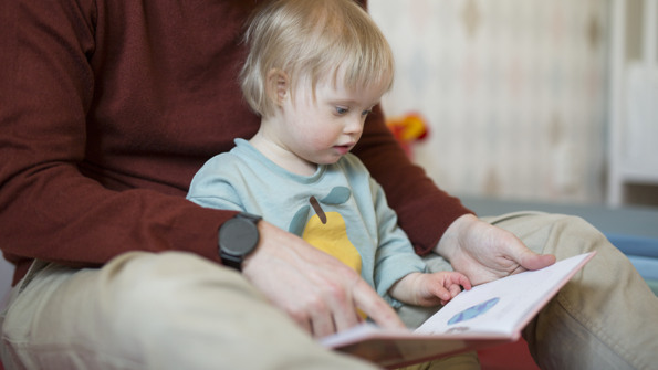 En man läser ut en bok för ett barn.