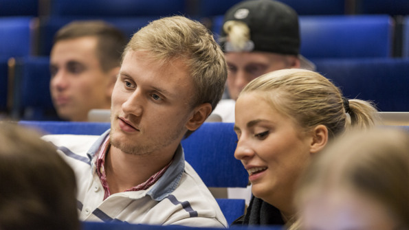 Två studenter, en man och en kvinna sitter i en aula.
