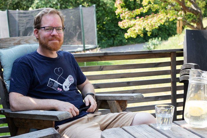 Erik Karlsson sitter på sin terrass i trädgården med en karaff med citronvatten och ett vattenglas på bordet framför sig.