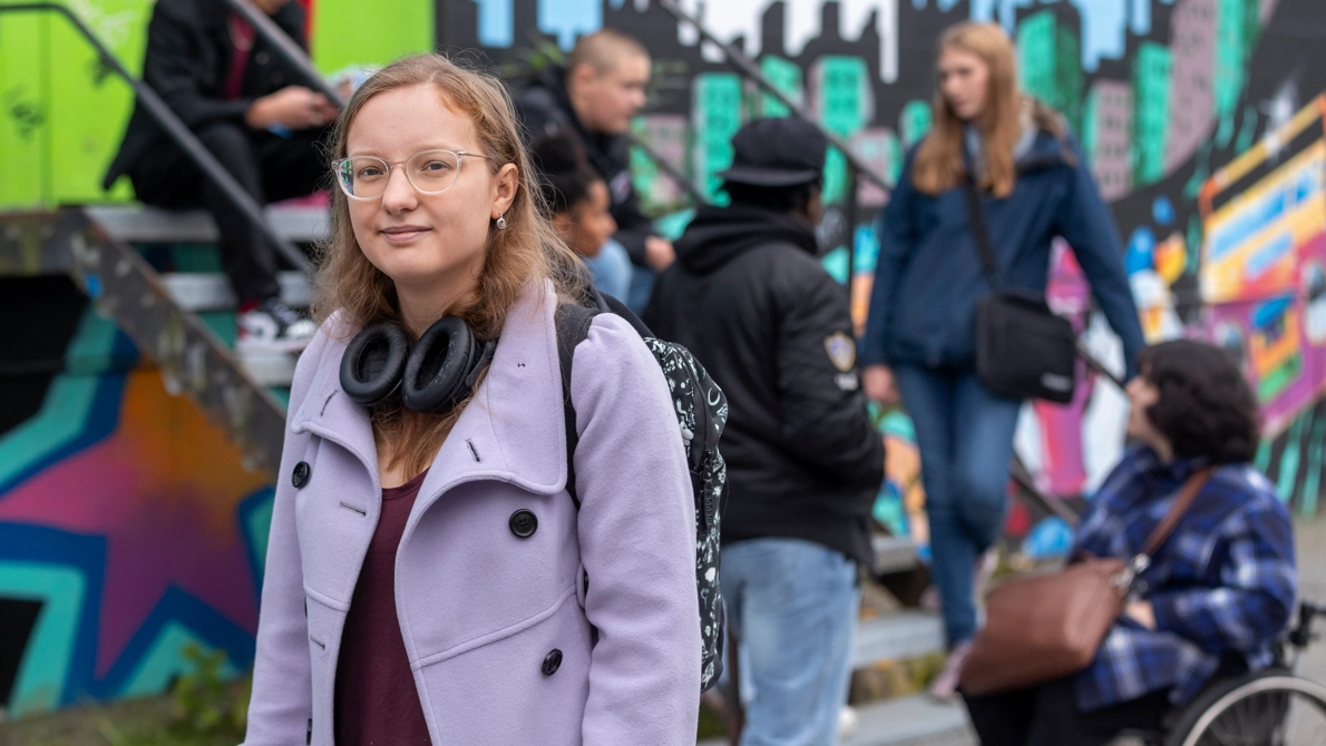 Kvinna i lila kappa och glasögon.