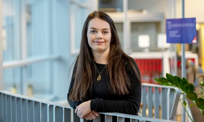 Petra står vid ett trappräcke i kontorsmiljö. 