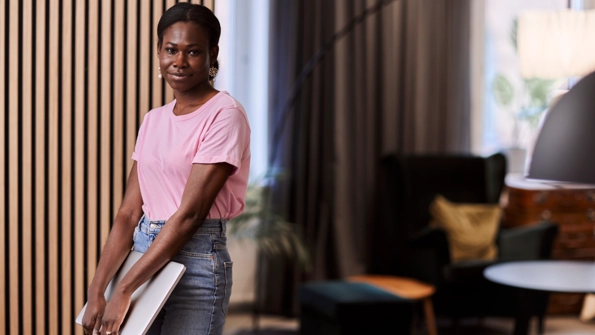 Kvinna i rosa tröja bär på en dator.